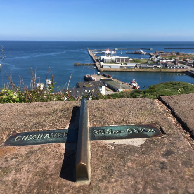 Beschilderung auf Helgoland, die zeigt, dass Cuxhaven 35 Seemeilen und damit 65 Kilometer von Helgoland entfernt ist. 
